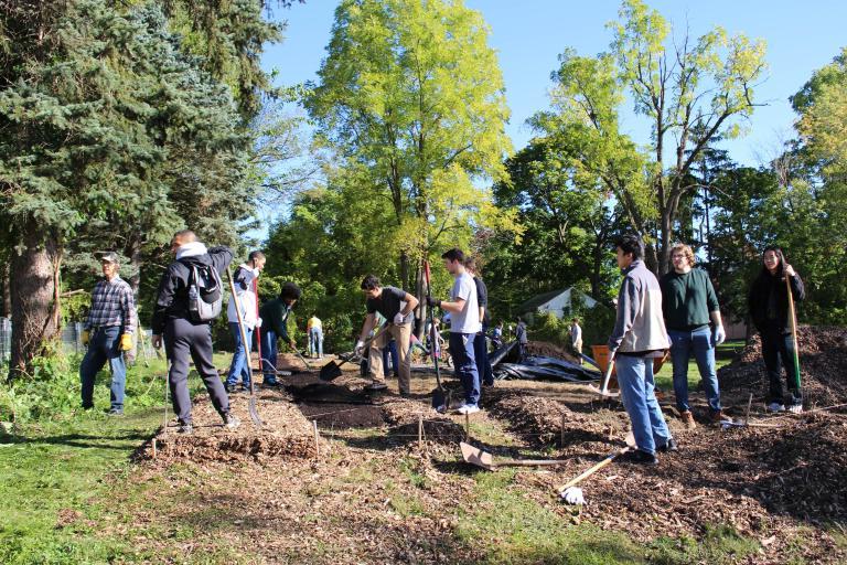 Kettering University students rake mulch in an area park.